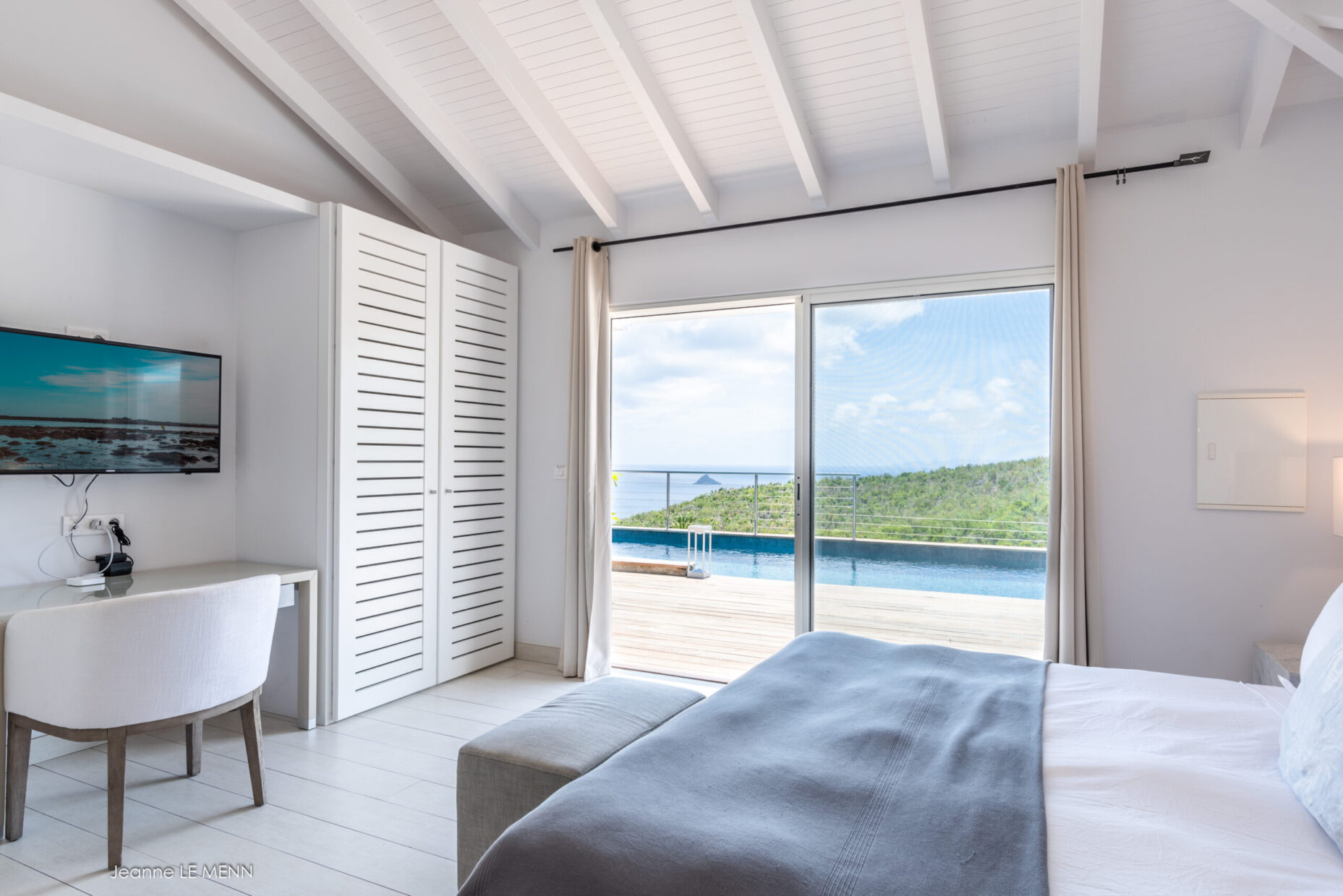 White bedroom opening to pool and sea.