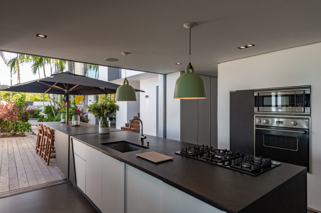 Open-plan kitchen at Villa Wings St. Barts with island and outdoor bar seating.