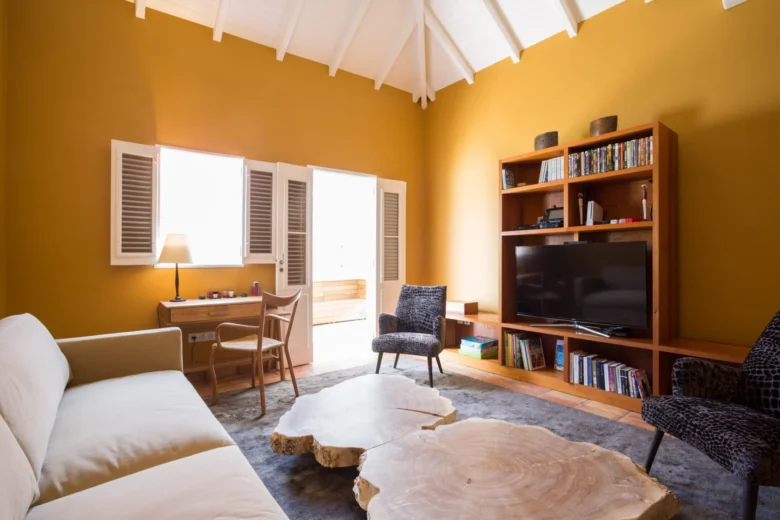 Yellow living room with a media center and unique log-slice coffee tables.