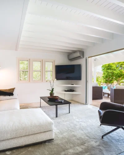 Modern living room with white sectional sofa opening onto a pool terrace with bay views.